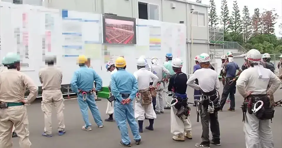 朝礼で現場の写真を大型ビジョンに映して共有している様子